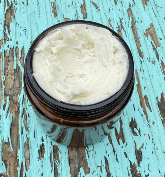 Jar of Calendula infused body butter with a wooden spoon, on a wooden surface