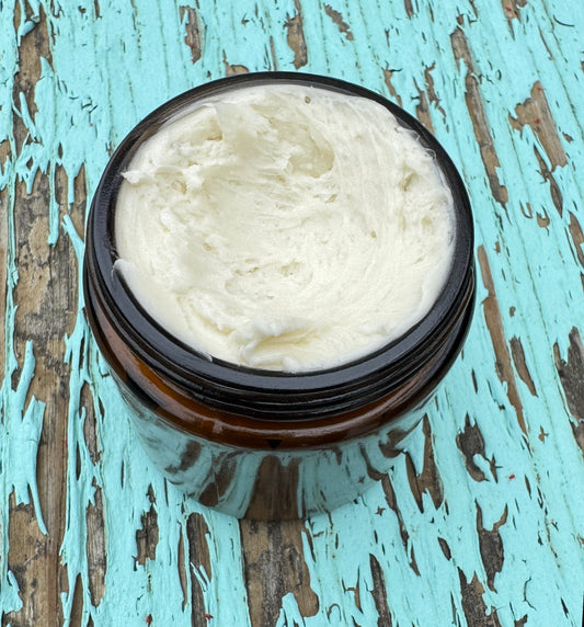 Jar of Calendula infused body butter with a wooden spoon, on a wooden surface