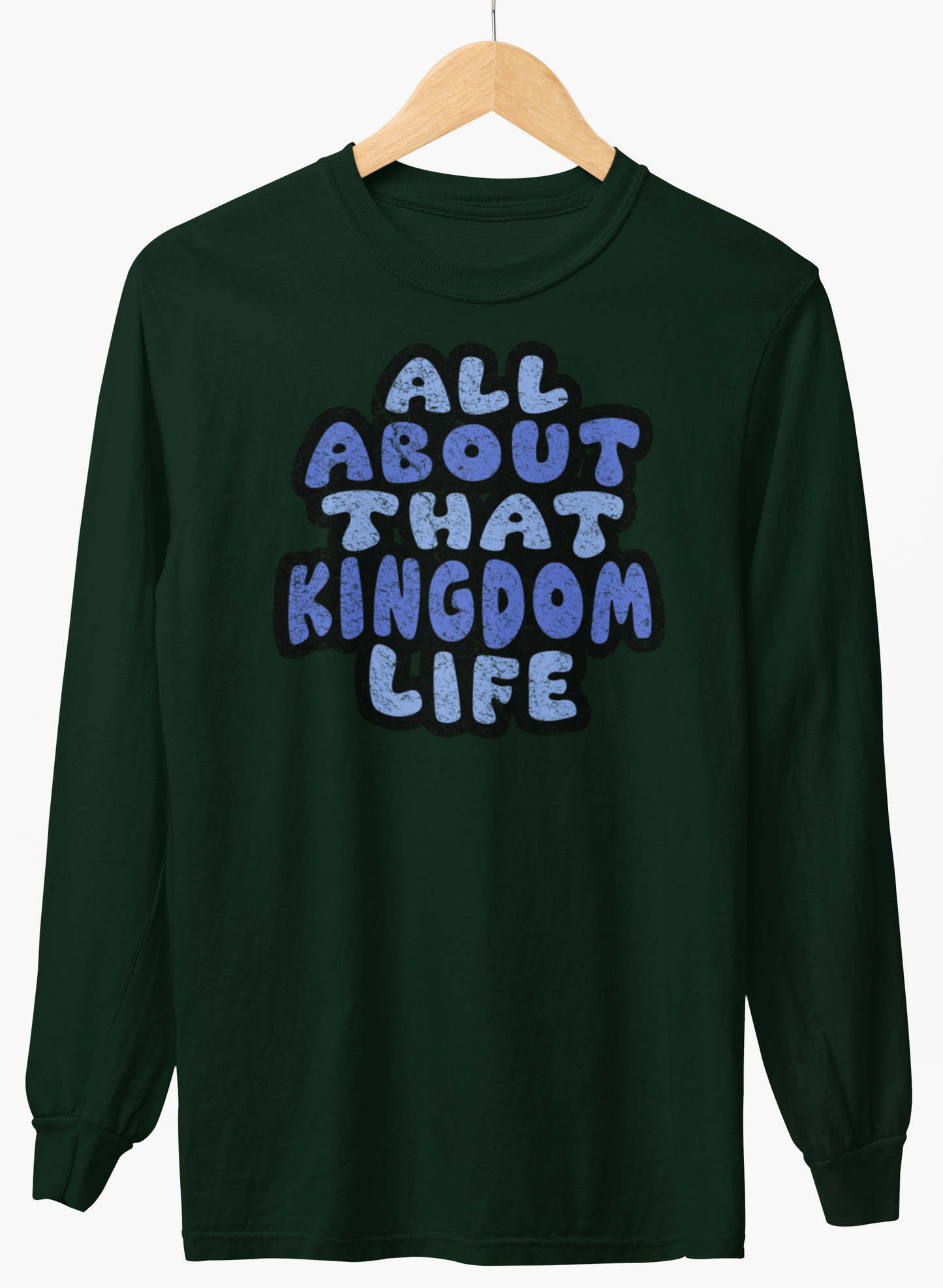 Forest green long-sleeve shirt with 'All About That Kingdom Life' distressed text on a hanger against a white background