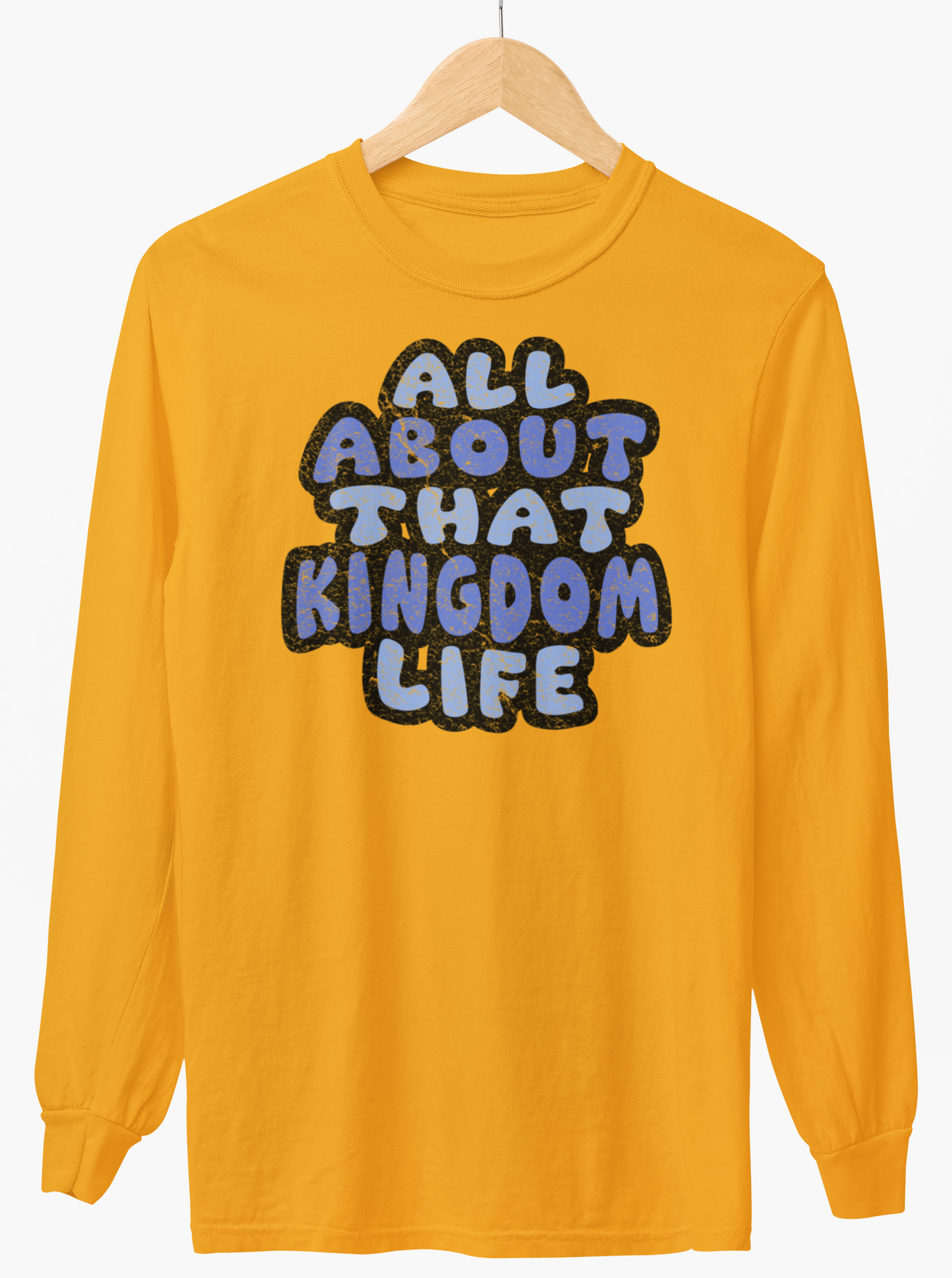 Gold  long-sleeve shirt with distressed text 'All About That Kingdom Life' on a hanger against a white background