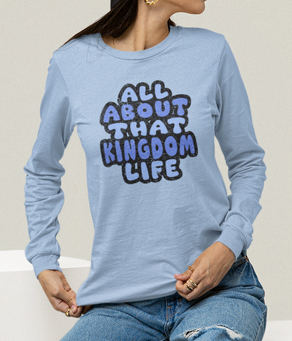 Woman wearing a light blue long-sleeve shirt with distressed text, sitting on white cubes.