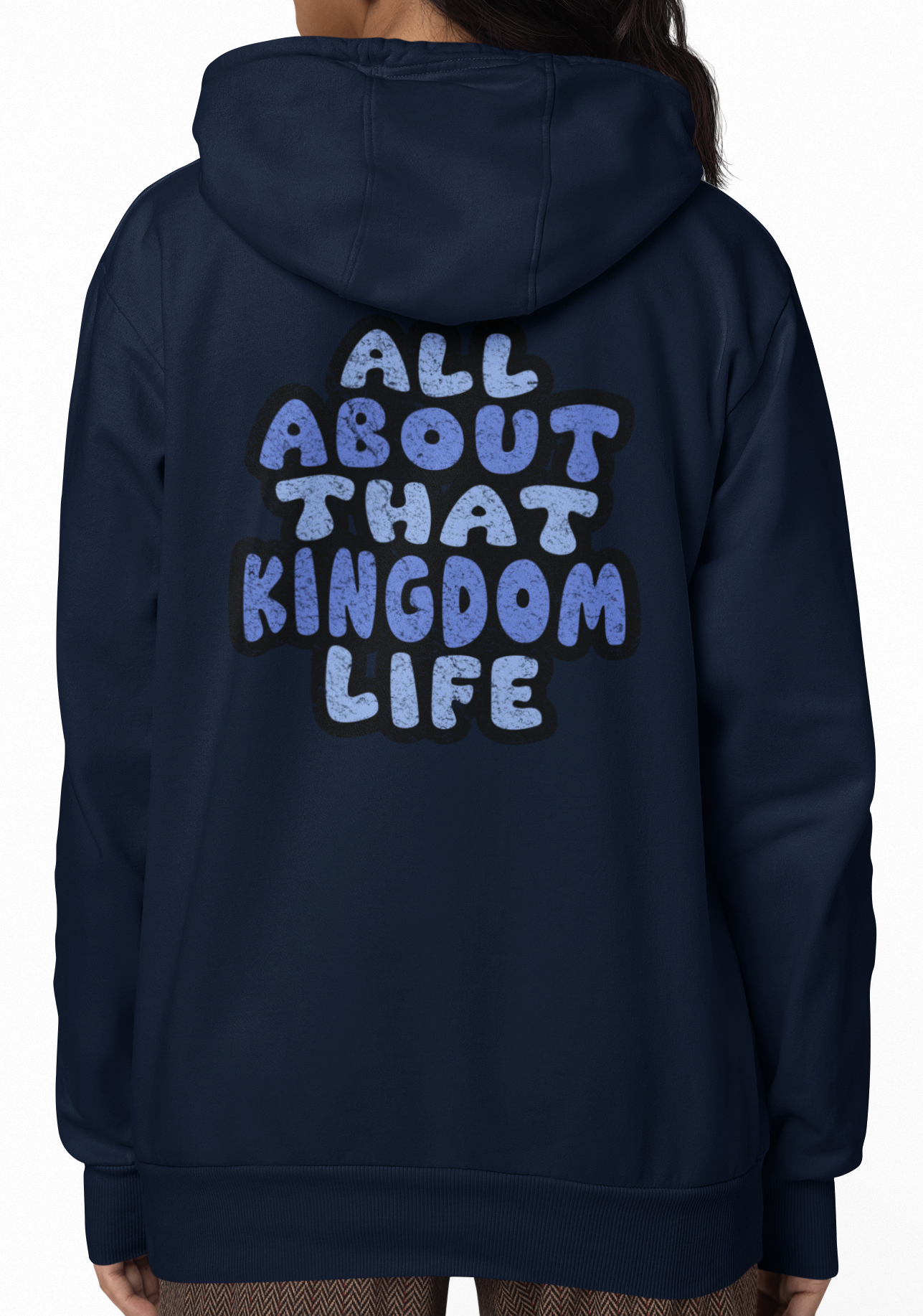 Woman wearing a navy hoodie with 'All About That Kingdom Life' distressed text on the back, standing against a white background.