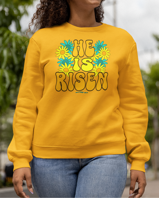 Woman wearing a gold 'He Is Risen' sweatshirt outdoors