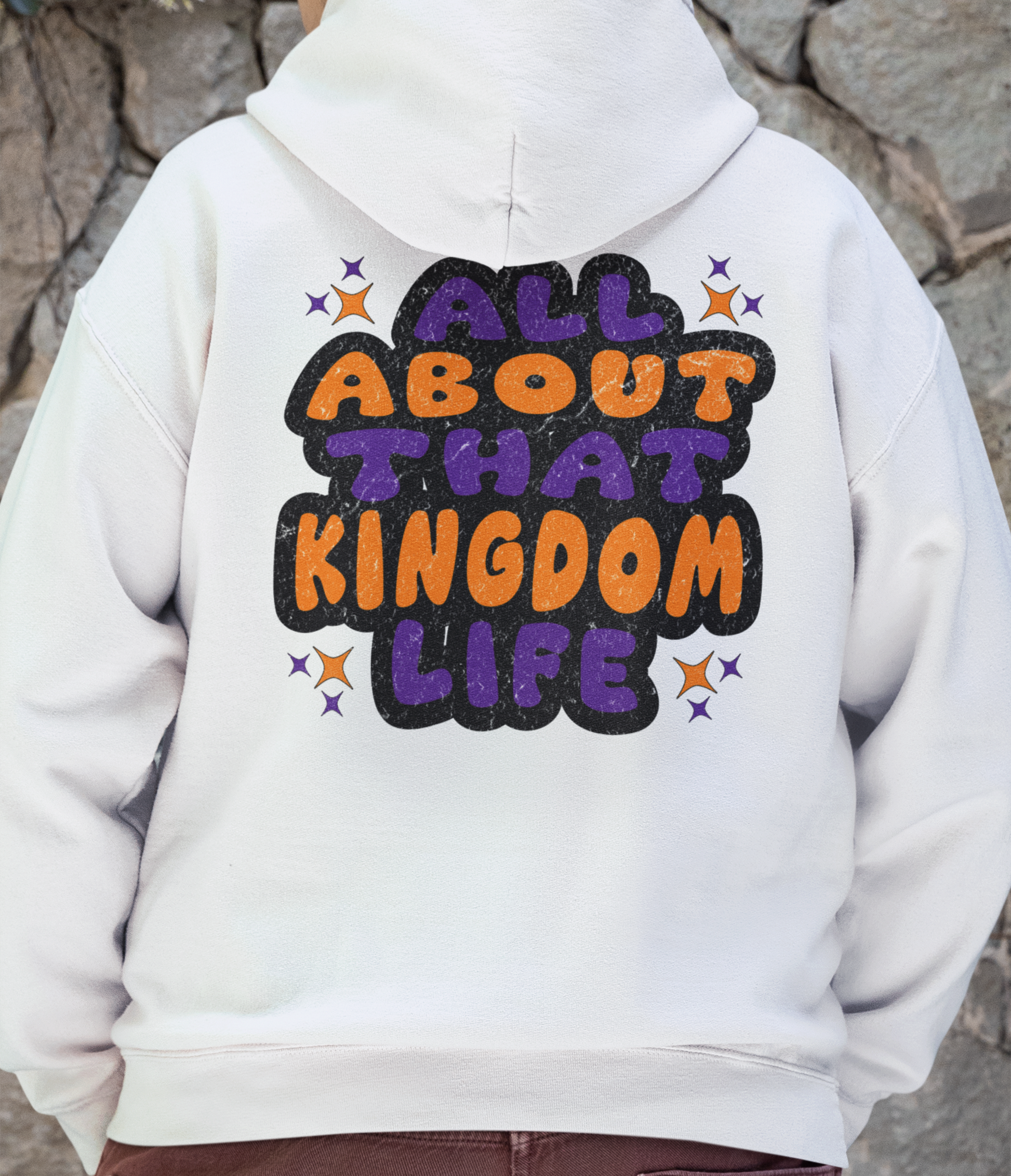 Man wearing a white hoodie with 'All About That Kingdom Life' distressed text on the back 
