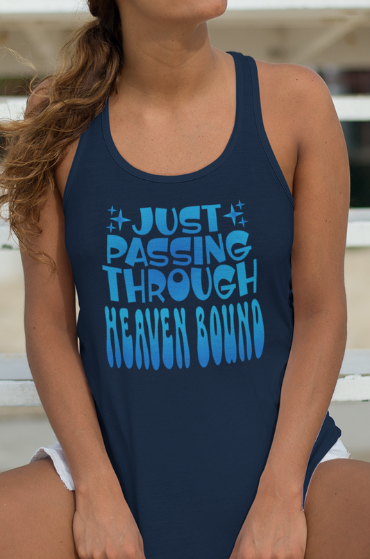 Woman wearing a navy blue women's racerback tank top with blue gradient text, 'Just Passing Through Heaven Bound'