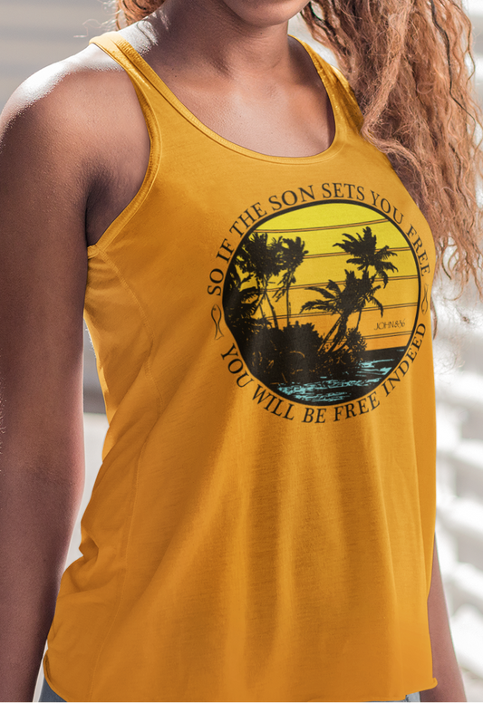 Woman wearing a gold women's racerback tank top with a palm tree design against a distressed sunset background