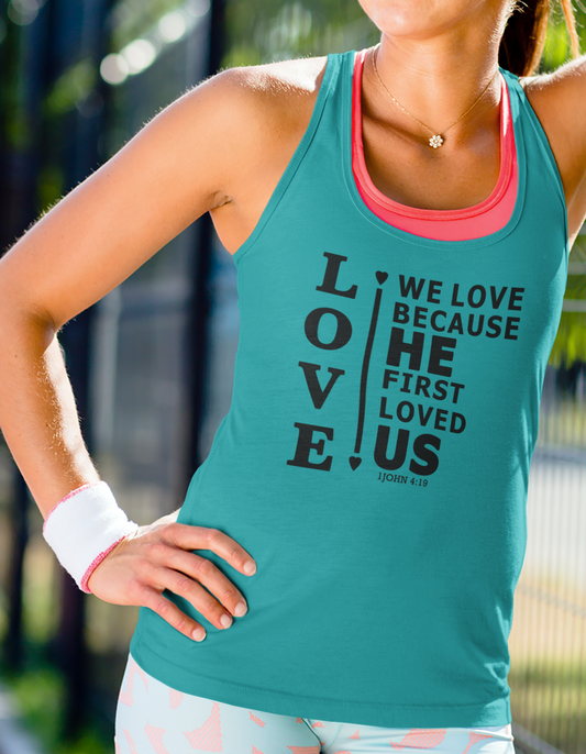 Woman wearing a teal women's racerback tank top with scripture verse 1 John 4:19