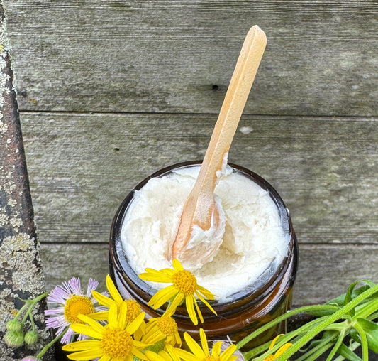 Suggestion
Jar of Calendula infused body butter with a wooden spoon, surrounded by yellow flowers on a wooden surface